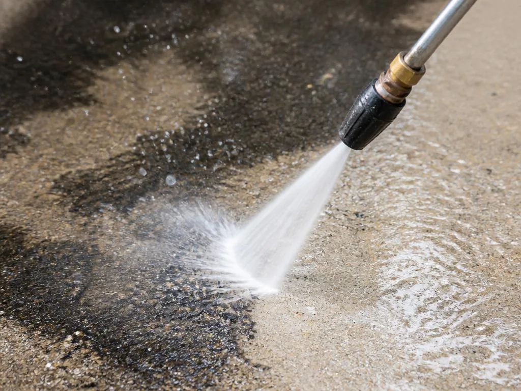 Close-up of pressure washing nozzle cleaning concrete